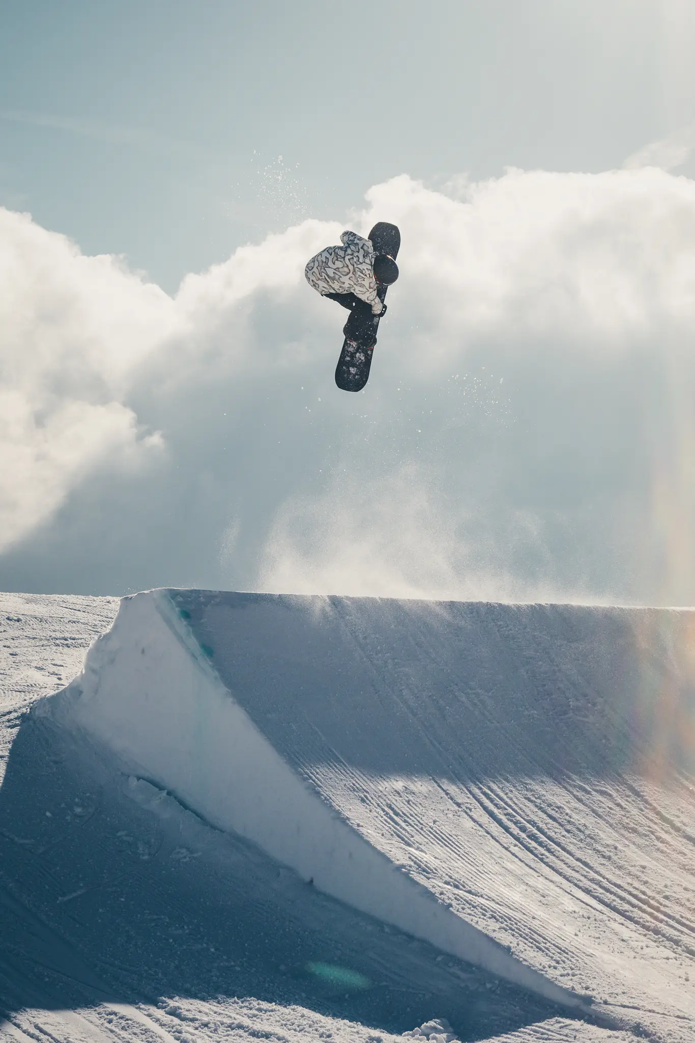 Snowboarder hoch über dem Kicker in den Wolken